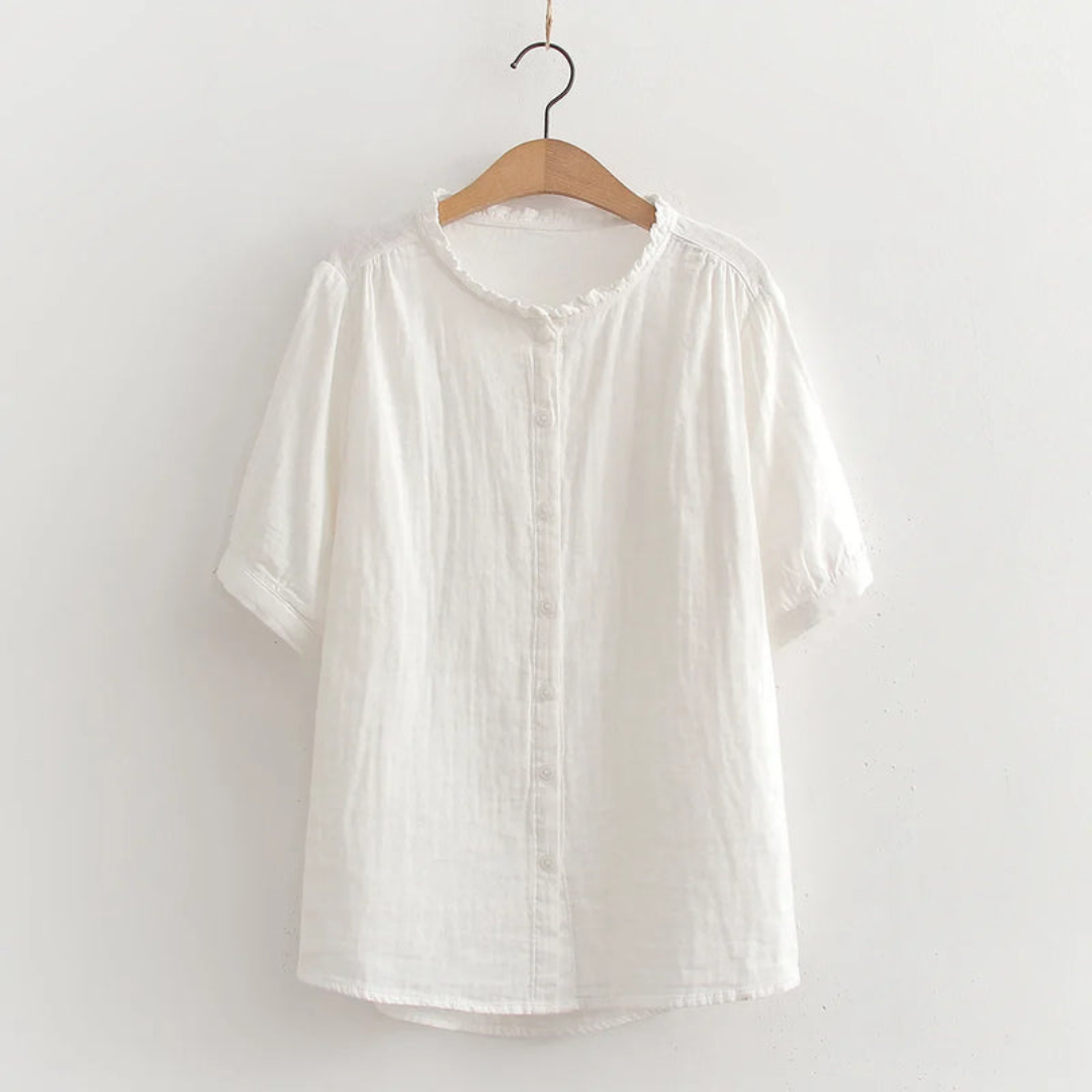 White button-up shirt with ruffled collar on wooden hanger, studio background.