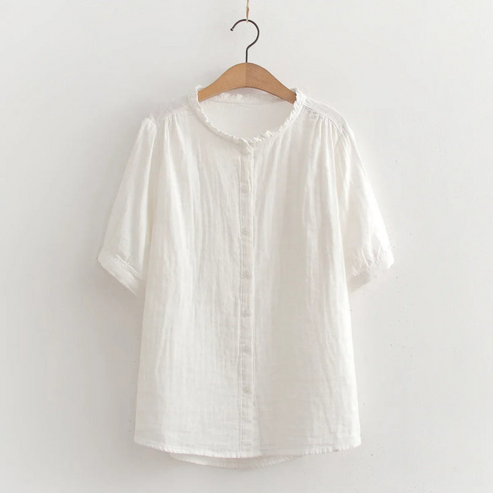 White button-up shirt with ruffled collar on wooden hanger, studio background.