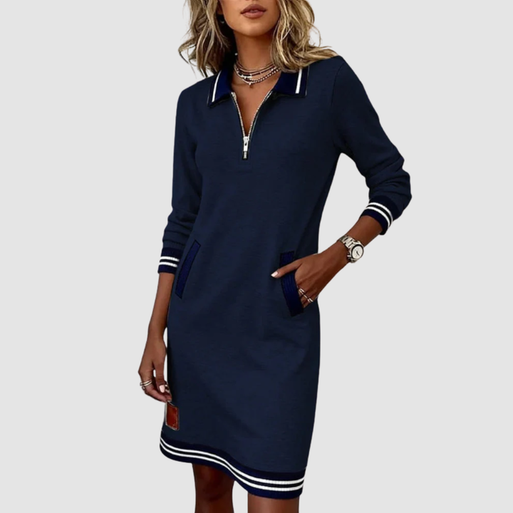 Stylish navy zip-neck dress with contrasting accents and pockets, showcased by a woman adorned with necklaces in a studio scene.