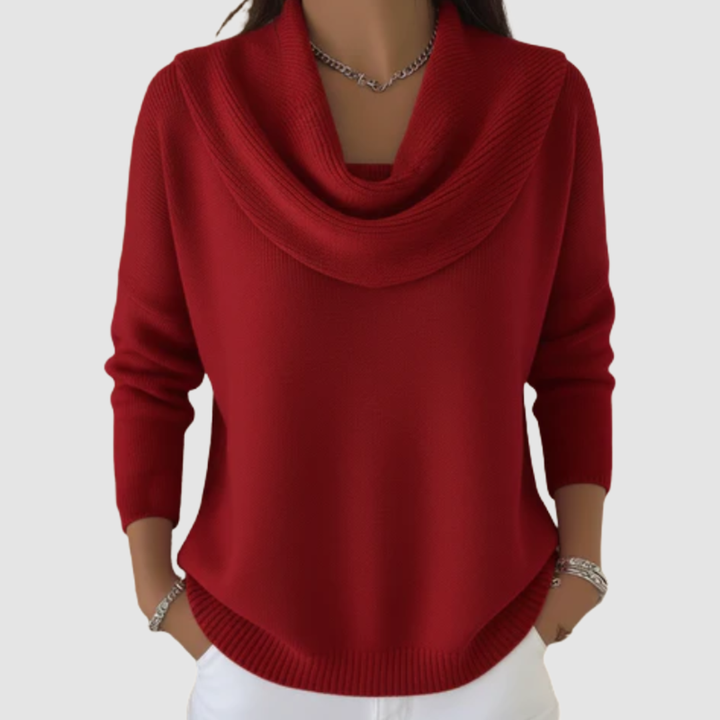 Red cowl neck sweater with long sleeves worn over white pants, displayed in a studio setting.