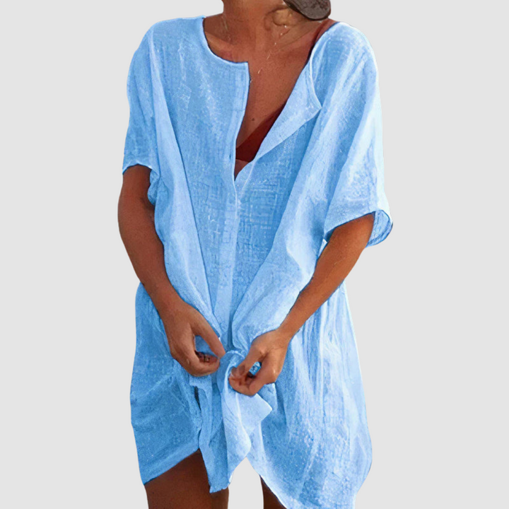 Blue loose fit dress with short sleeves and textured fabric, worn by person with untied front, studio background.