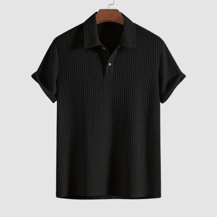 Black textured polo shirt on a hanger against a plain light gray background.
