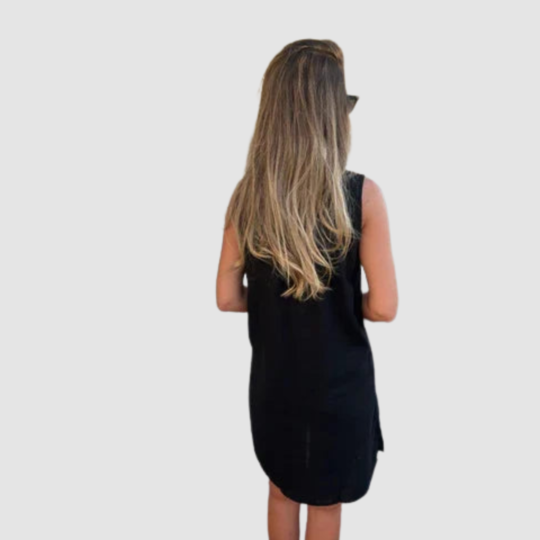 Back view of a woman in a black sleeveless dress, showing long hair against a studio backdrop.