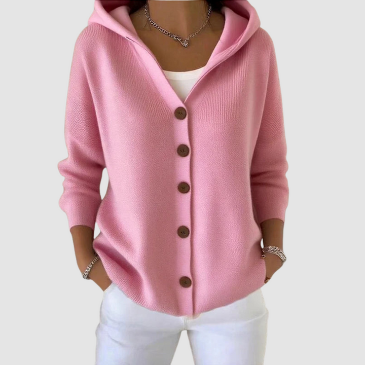Pink hooded cardigan with brown buttons, worn over a white top, against a light gray background.
