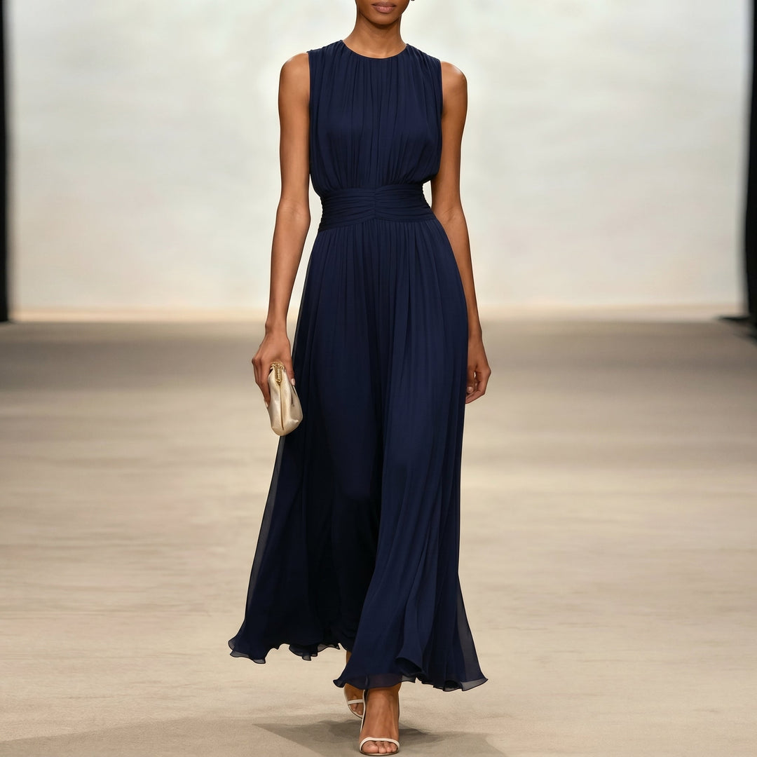 Dark blue elegant dress, flowing design, model with clutch in indoor setting.