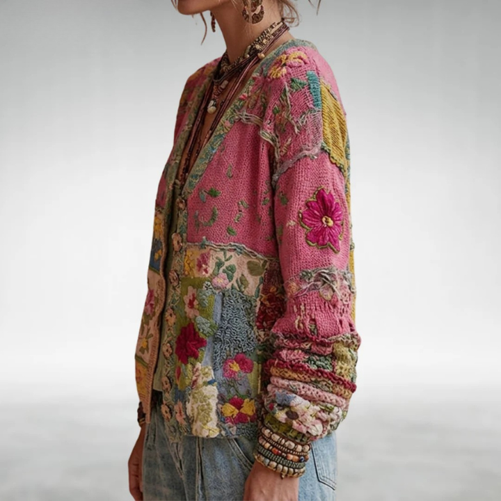 Side view of colorful, patchwork knit cardigan with floral designs, worn with jewelry in a studio setting.