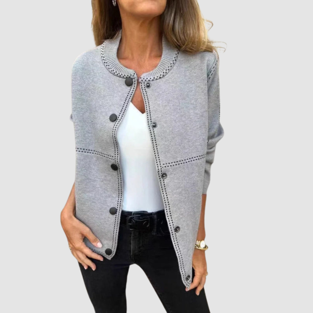 Gray jacket with round collar, button closure, worn over white top and black pants in a studio setting.