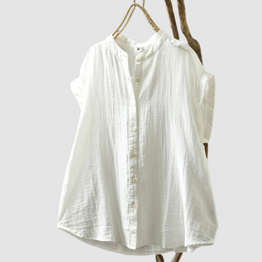 White vintage shirt with subtle texture, short sleeves, and buttons, hanging on a rustic branch against a gray background.