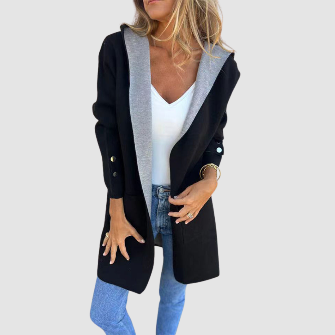 Black and gray colorblock hooded jacket worn over white top and jeans in a studio setting.