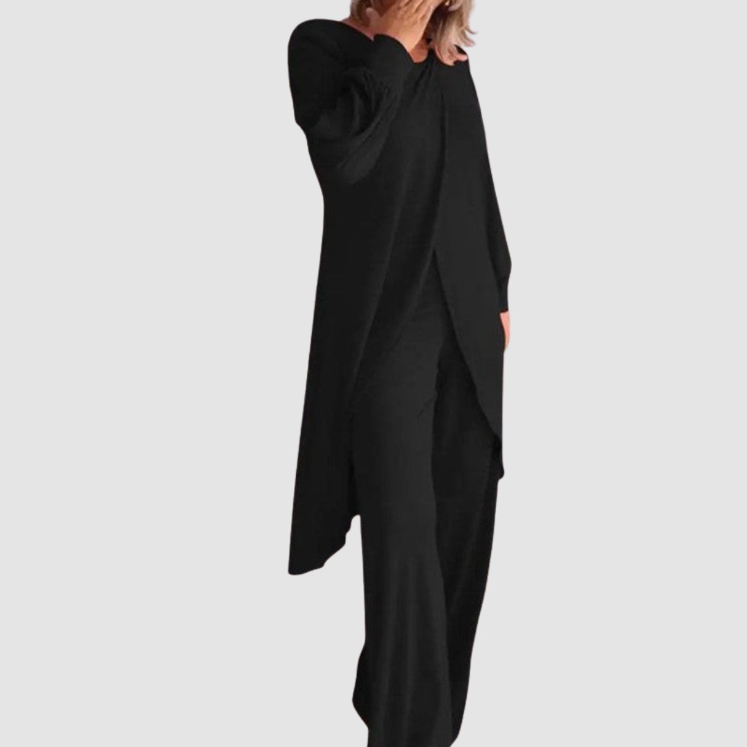 Model wearing a black long-sleeve 2-piece set in a studio, hand covering face, white background.