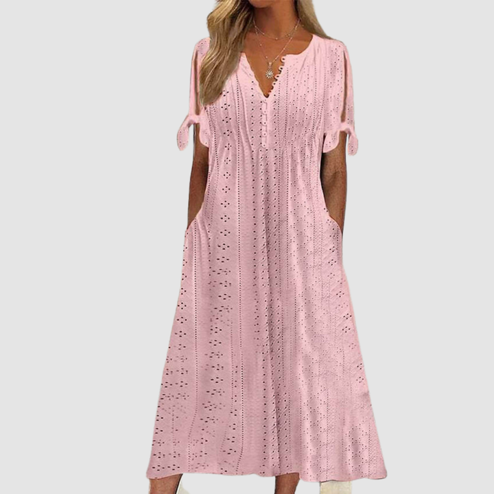 Pink elegant casual dress with eyelet details and tie sleeves, presented in a studio setting.