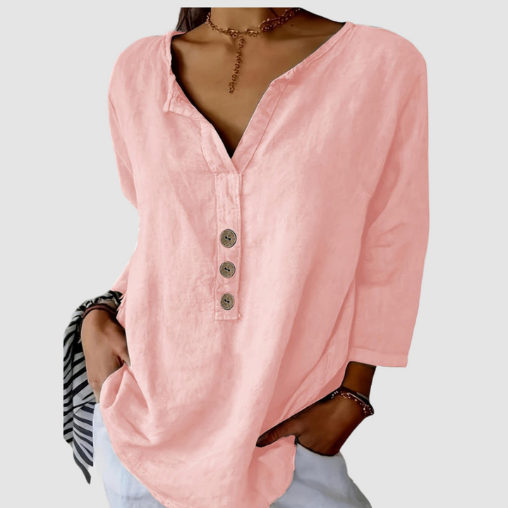 Casual pink blouse with button detail, worn by a model with a choker, against a plain background.