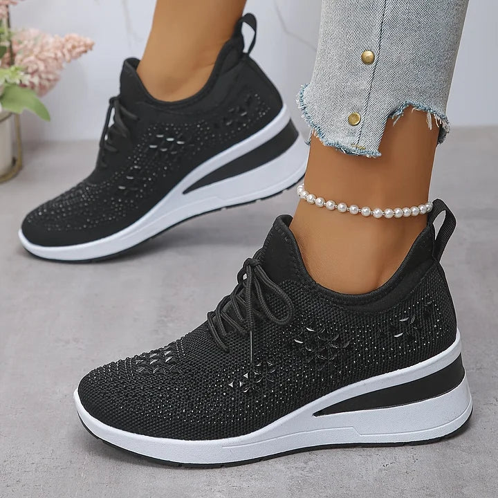 Black orthopedic sneakers adorned with stylish textures, matched with jeans, in a soft-toned indoor environment.
