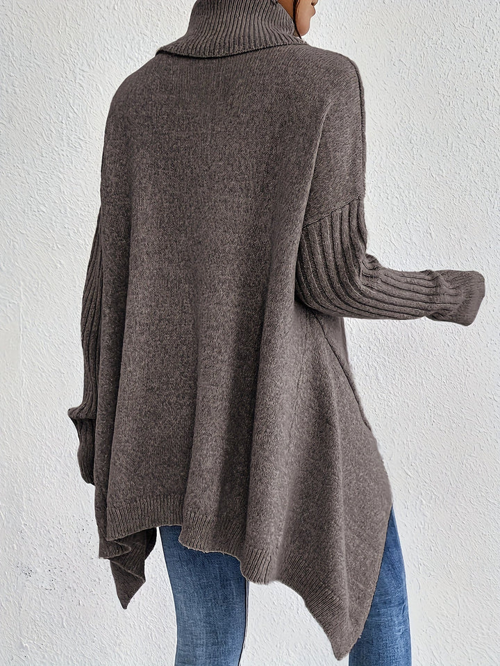 Back view of brown turtleneck sweater with ribbed sleeves, styled with jeans, against a plain white wall.