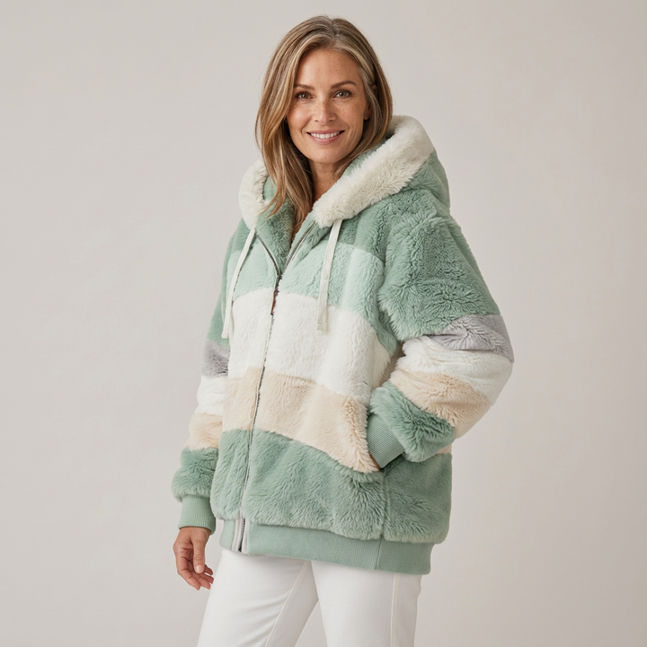 Woman wearing a plush, multicolored hooded jacket in white, green, and beige stripes, in a studio setting.