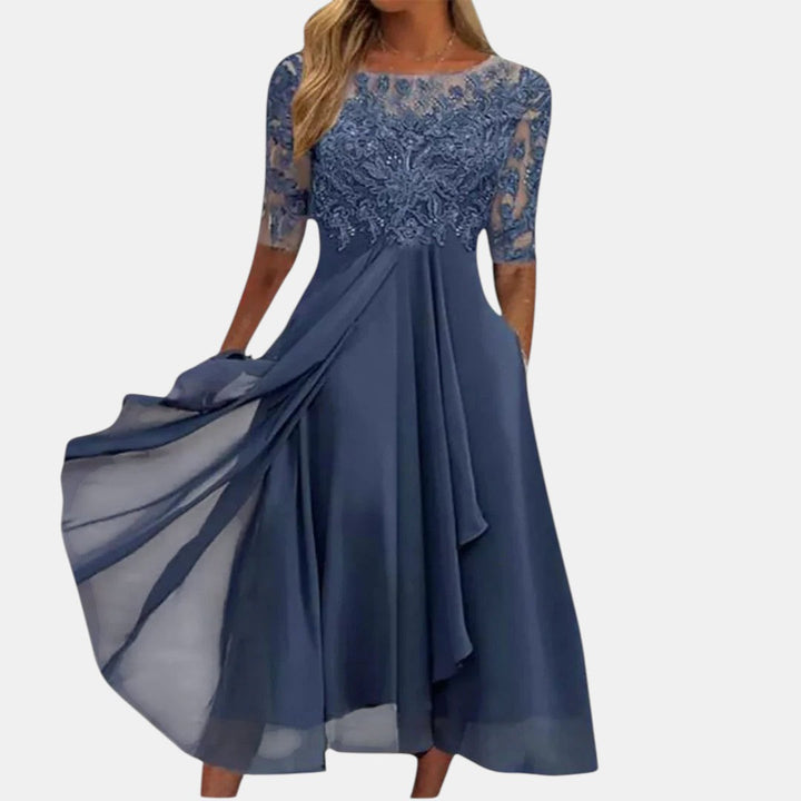 Elegant blue dress with lace bodice and flowing skirt, studio background.