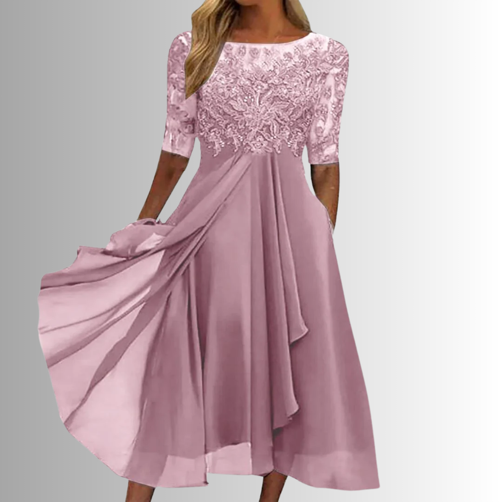 Elegant pink lace dress with sheer sleeves in a studio setting.