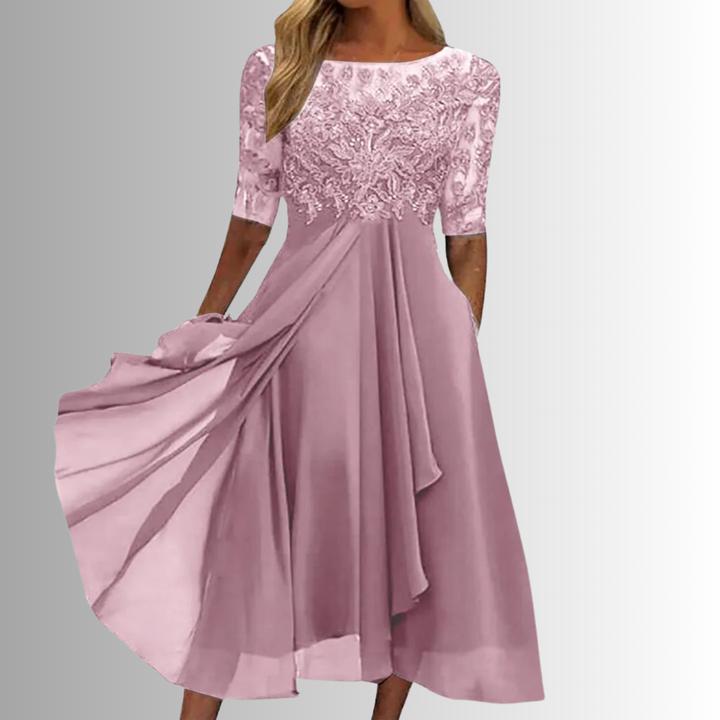 Elegant pink lace dress with sheer sleeves in a studio setting.