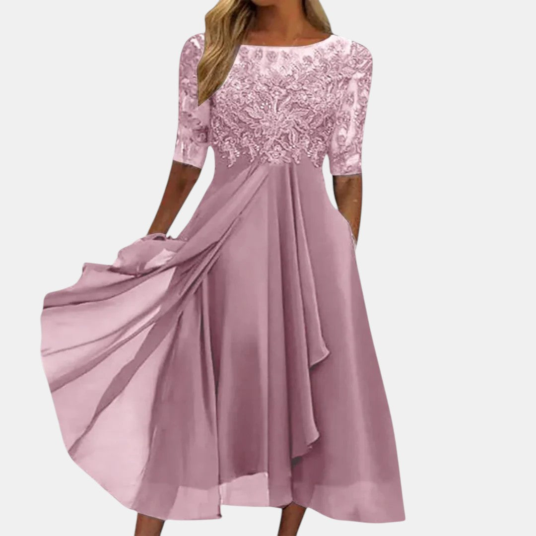 Elegant pink dress with lace bodice and flowing skirt, studio background.