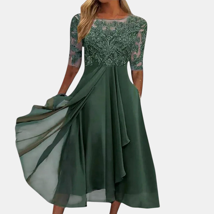 Elegant green dress with lace bodice and flowing skirt, studio background.