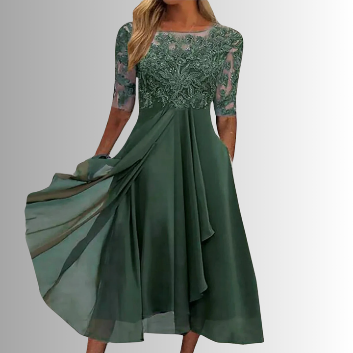 Elegant green lace dress with sheer sleeves in a studio setting.