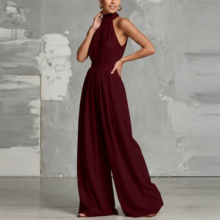 Stylish burgundy jumpsuit with a halter neck and wide legs in a modern studio setting.