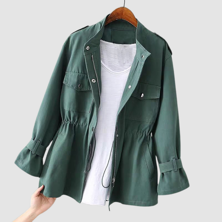 Dark green jacket with button accents, adjustable waist, and pockets, displayed on a wooden hanger with a light background.