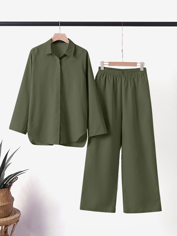 Green two-piece outfit hanging on a hanger in a bright indoor setting with wicker basket plant.