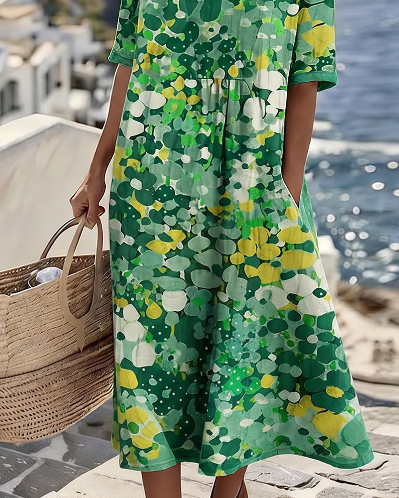 Close-up of green floral midi dress by the sea, model with wicker bag, coastal view in background.