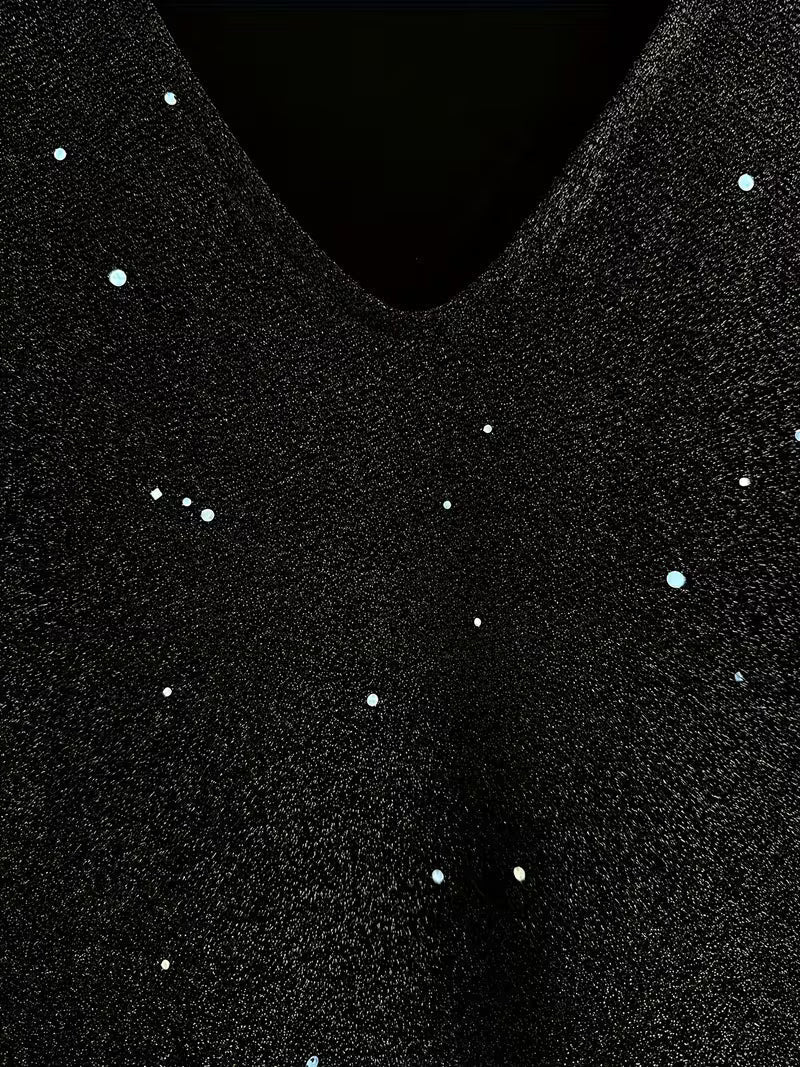 Close-up of a black dress fabric with shimmering detail and V-neckline, highlighting texture and sparkle.