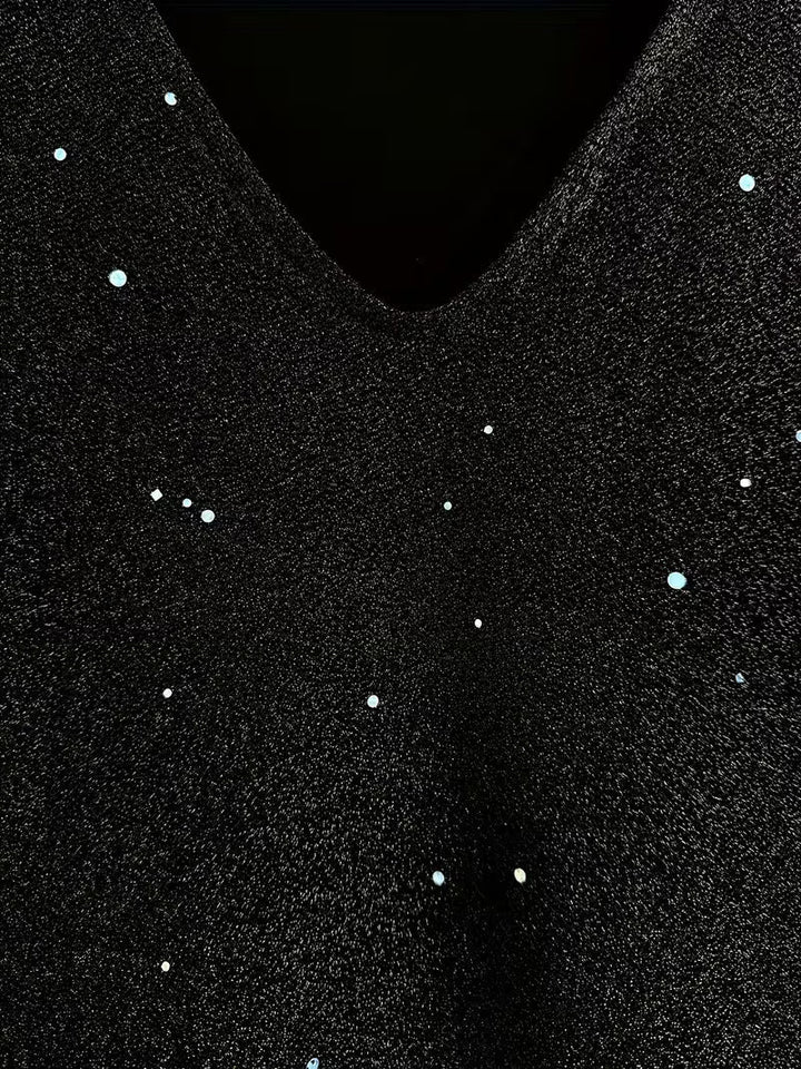 Close-up of a black dress fabric with shimmering detail and V-neckline, highlighting texture and sparkle.