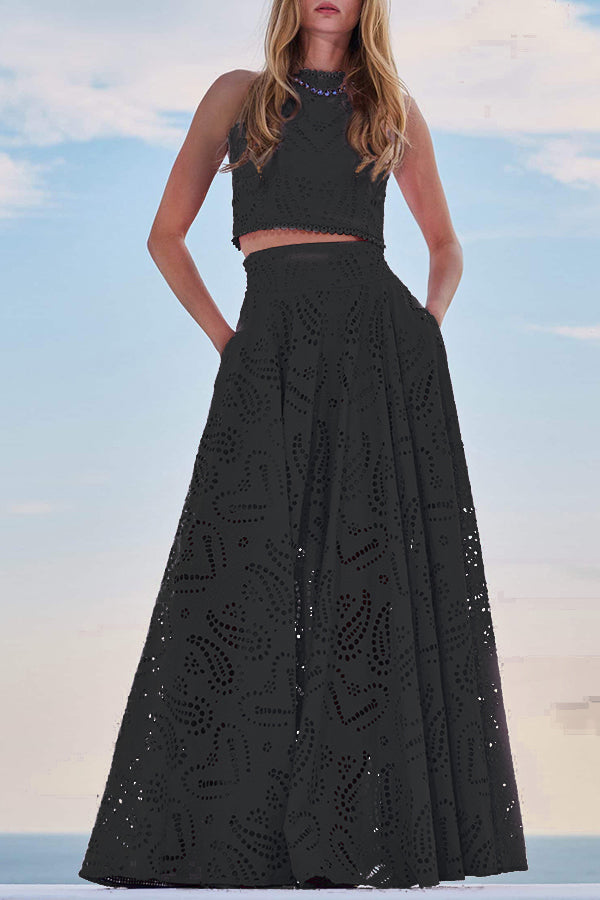 Model posing in a black embroidered top and maxi skirt set against a scenic sky backdrop.
