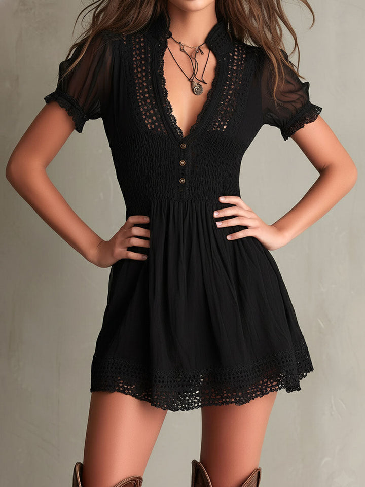Front view of black mini dress with lace trim, smocked bodice, and short sleeves against a neutral background.