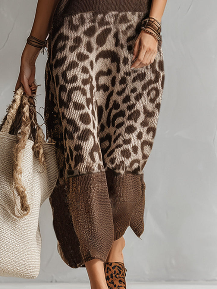 Close-up of the skirt section of a knitted leopard print dress with brown accents, showing a textured tote bag, in a studio setting.