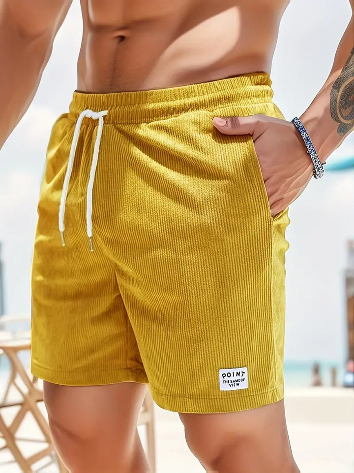 Close-up of yellow swimming trunks with drawstring, worn by model on a sunny day.