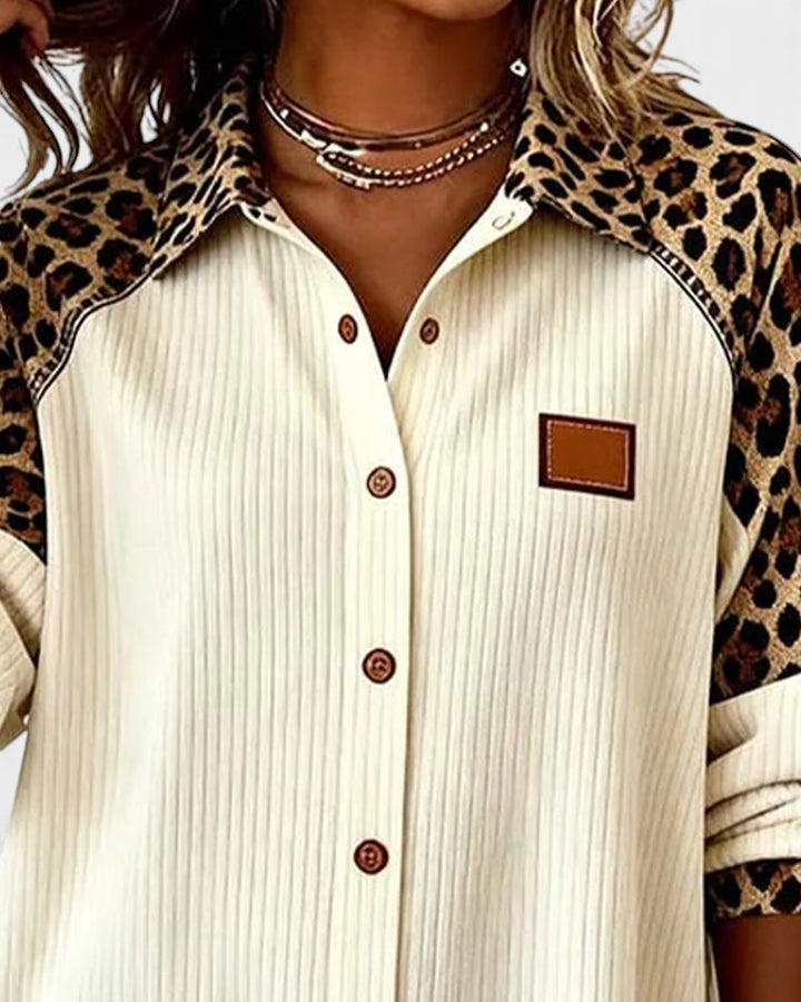 Close-up of leopard print button-down shirt top. Cream shirt with patterned collar and brown buttons in a studio.