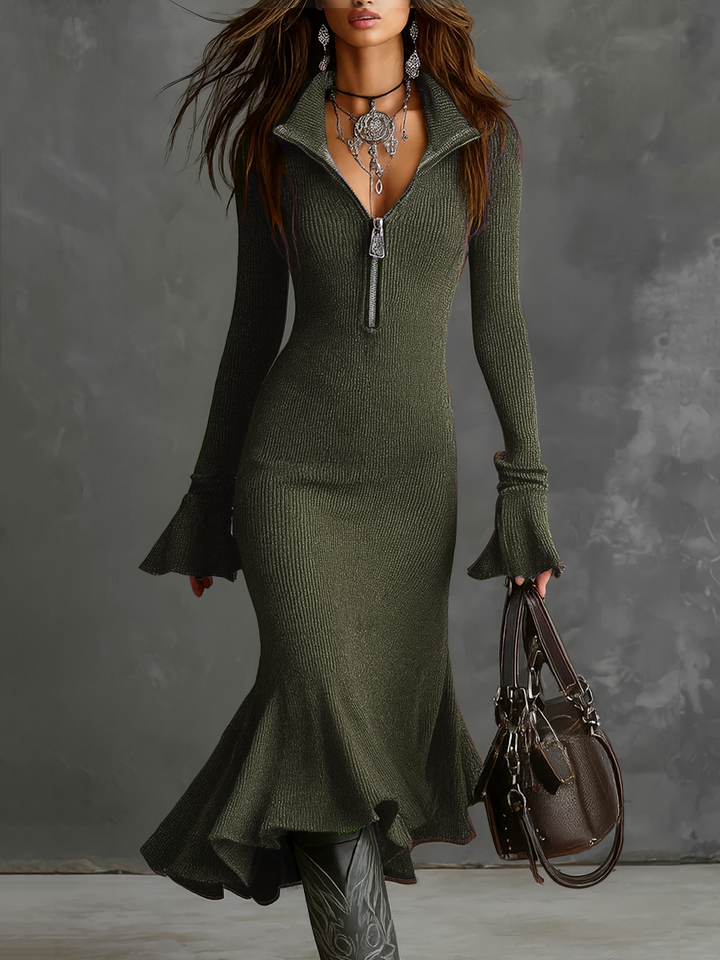 Retro zip neck knit midi dress in green with flared cuffs and ruffled hem, accompanied by a handbag. Studio background.