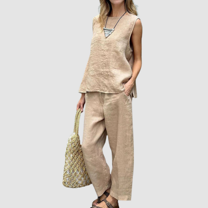 Light tan two-piece summer set with sleeveless top and loose pants, model holding a woven bag, gray background.