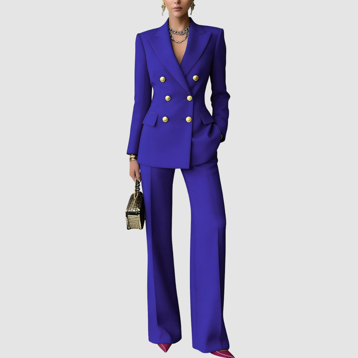 Vibrant blue tailored set with gold buttons, structured blazer, wide-leg pants, worn with statement jewelry and a metallic handbag on a gray background.