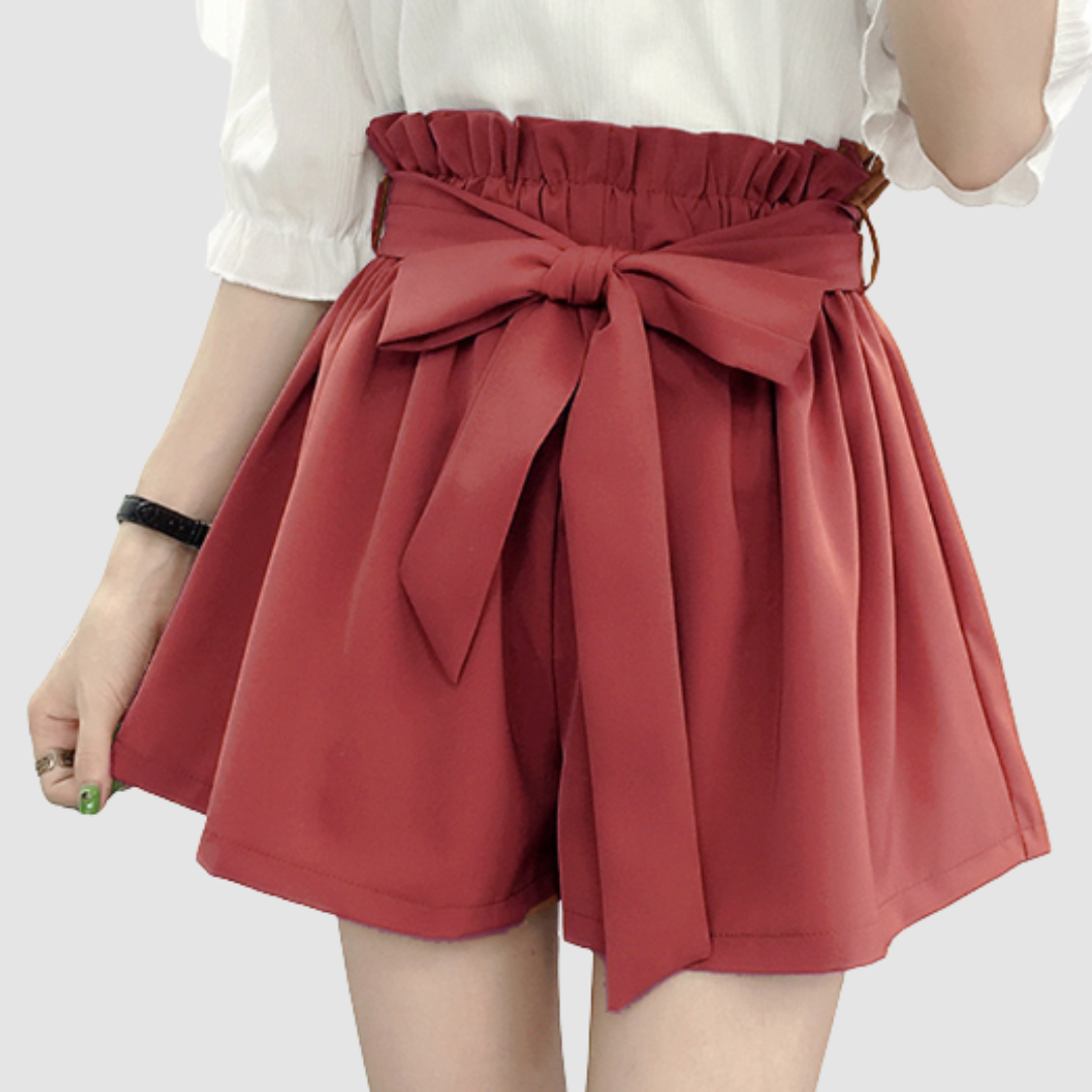 Red paperbag waist shorts with a bow, paired with a white top in a studio background.
