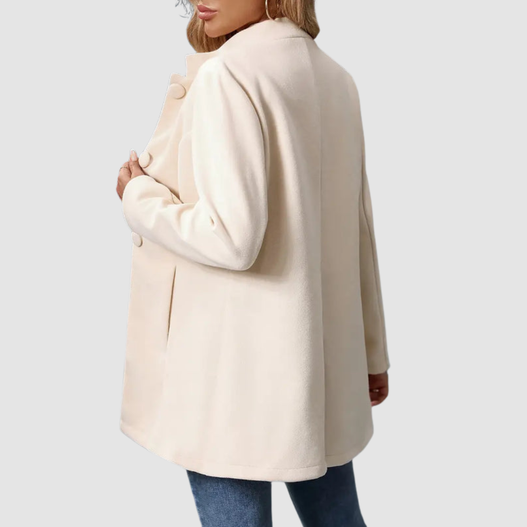 Back view of light beige jacket with large buttons, worn over jeans, against a plain background.