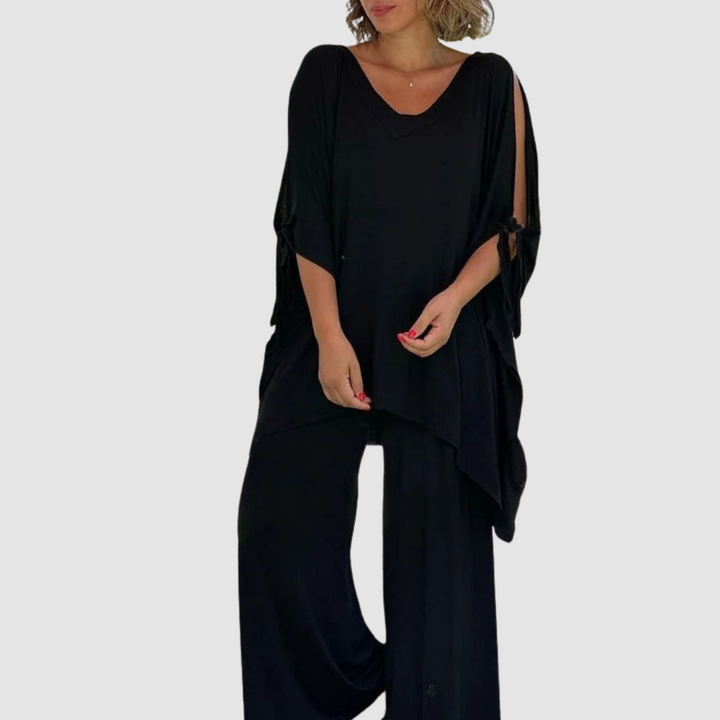 Woman wearing a chic black relaxed style set featuring a flowing top and wide-leg pants, on a plain background.
