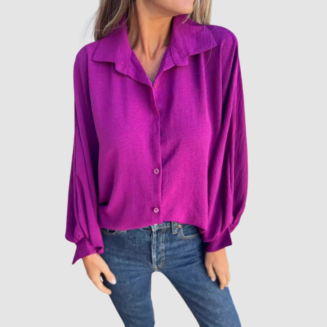 Model wearing a purple oversized blouse with buttons, blue jeans, gray background.