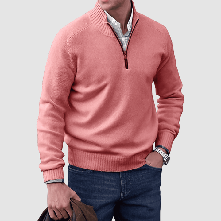 Model in pink zip pullover with ribbed collar and cuffs, holding a jacket. Paired with jeans, set against a plain background.