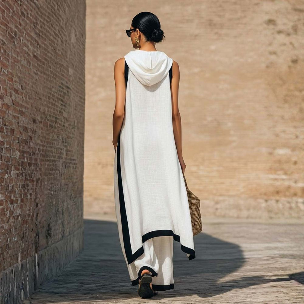 Back view of elegant white outfit with black trim, worn by a person with a bun hairstyle, outdoor brick wall backdrop.