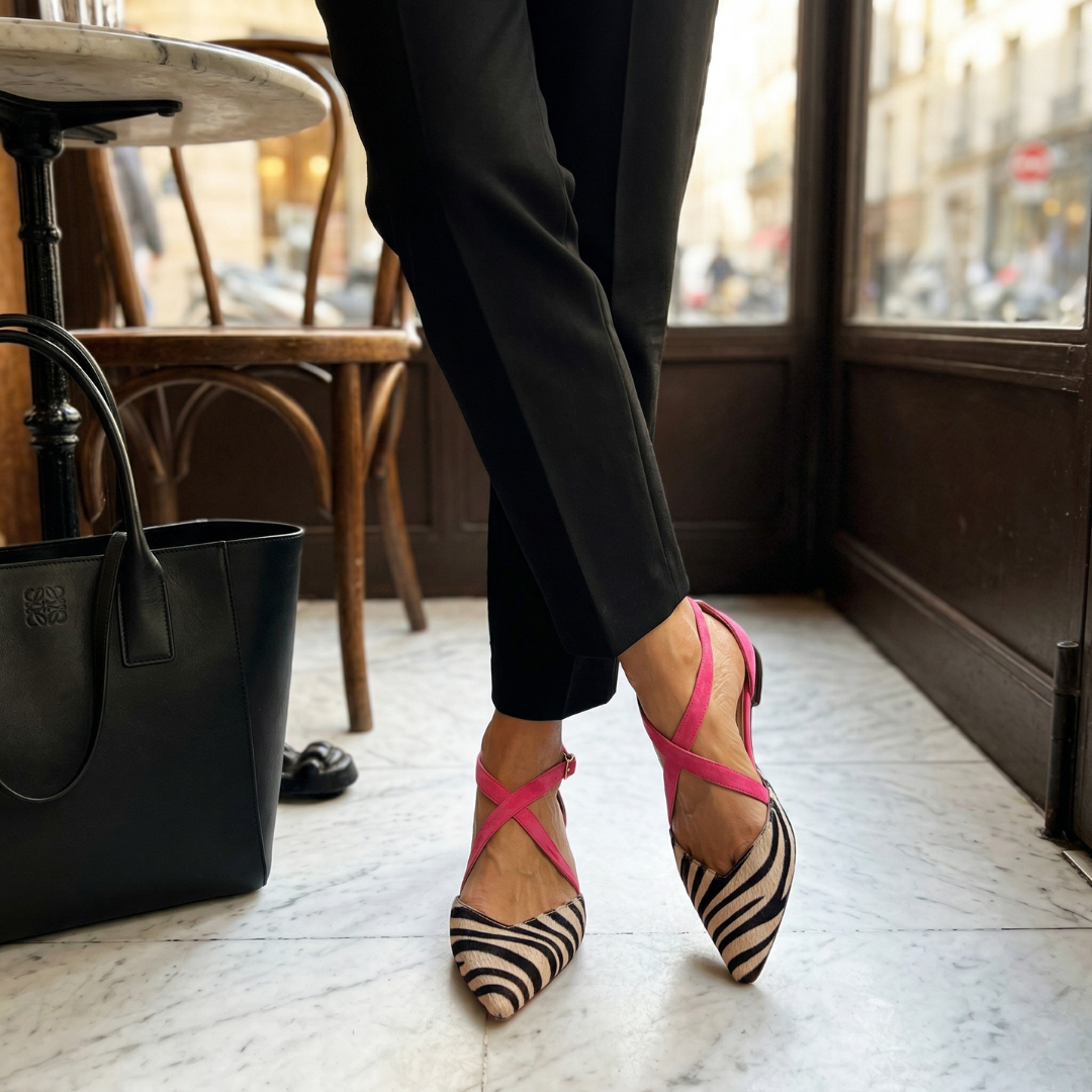 Pink zebra ballet flats worn in a cozy café setting with dark pants.