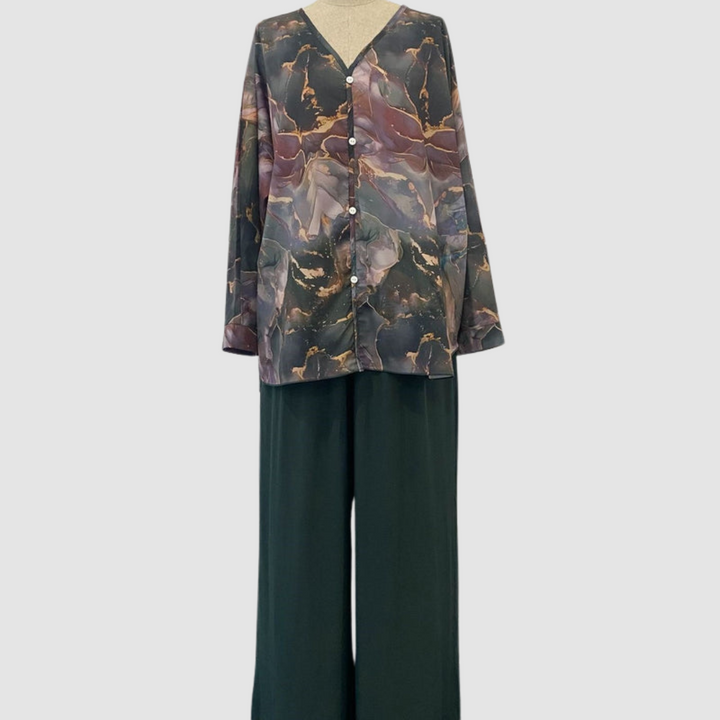 Mannequin displaying an elegant printed two-piece set with a button-up top and flowing pants, set against a plain background.