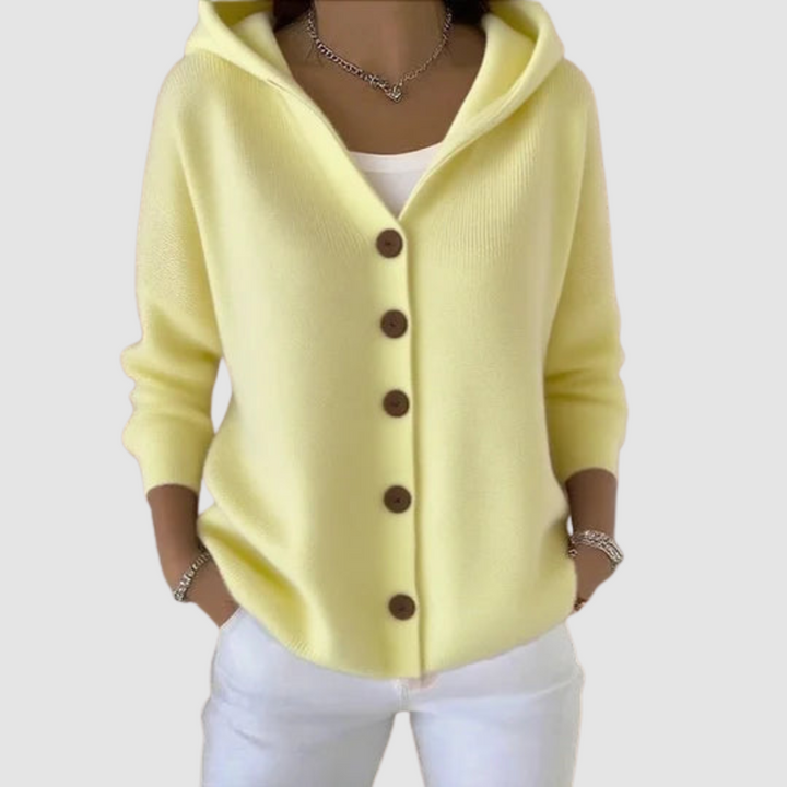 Yellow hooded cardigan with brown buttons, worn over a white top, against a light gray background.
