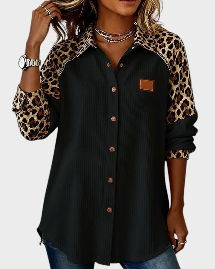 Leopard print button-down shirt in black with brown buttons. Patterned collar and sleeves. Worn by model in a studio.