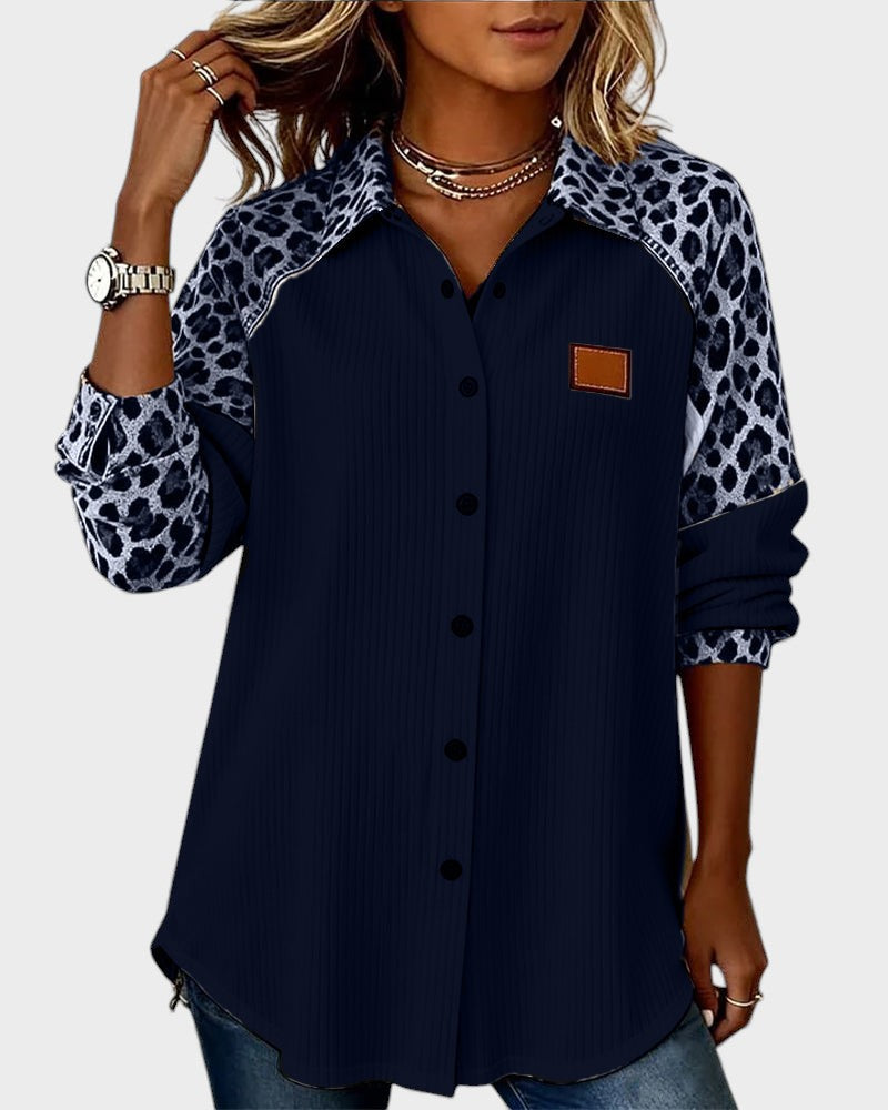 Leopard print button-down shirt in navy with black buttons. Patterned collar and sleeves. Worn by model in a studio.